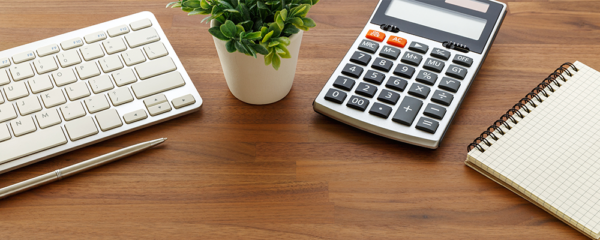 Keyboard, calculator, and notebook on a desk