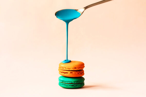 Liquid paint spills from a spoon on a macaroon